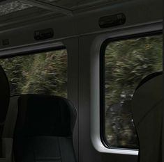 an empty train car with two seats facing the window and trees outside in the background