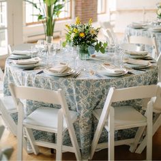 the table is set with place settings and flowers in vases on each side of the table