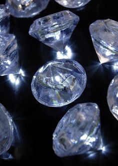 many clear diamonds are arranged on a black surface with light coming from them in the middle