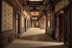 an empty hallway with wooden paneling and ornate wallpaper