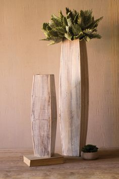 two wooden vases sitting on top of a table next to a potted plant