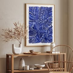 a blue and white artwork hangs above a wooden shelf