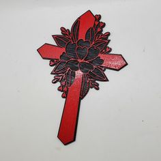 a red and black cross with a flower on the center is shown in this image