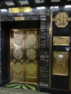 the doors to an elevator are decorated with gold and black panels, along with decorative wall hangings