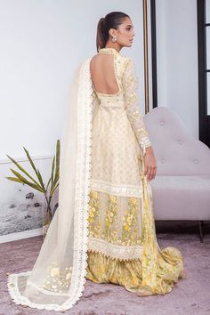 This festive silhouette is cut from cotton net in a refreshing lemon and is detailed with gota and floral embellishments. The look is completed with an organza chatta-pati dupatta with hues of lavender, teal and blush pink with triangular gota finishing and a gold brocade izaar. A piece that is a timeless wardrobe clas Beige Gota Work Anarkali Set For Wedding, Beige Anarkali Set With Gota Work For Wedding, Cream Sharara With Sheer Dupatta For Diwali, Eid Off-white Dresses With Gota Work, Bollywood Style Cream Dress With Sheer Dupatta, Eid Off White Gota Work Dresses, Off White Dress With Gota Work For Eid, Off-white Gota Work Dresses For Eid, Festive Off-white Dupatta With Gota Work