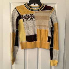 a yellow and brown sweater hanging on a door