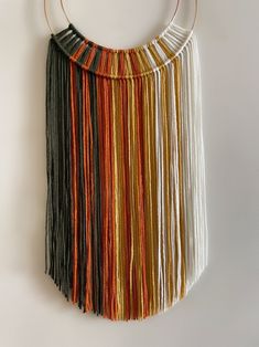 a multicolored necklace hanging on a white wall