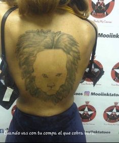 the back of a woman's body with a tattoo of a lion on it