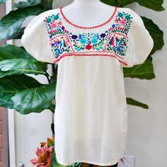 "The Yucatan embroidered top is beautifully made in Merida Yucatan, Mexico, each piece is  fully hand embroidery. Details: Size S/M - measurements: Bust: 40\" - 27.5\" length(shoulder to bottom Hem) - Cotton  thread Embroidered - Material: 100% Cotton - split sides - All items are shipped from the US All Mi Mundo Mexicano  items are 100% handmade by artisans in Mexico. Each stitch and item is completely unique and one-of-a-kind, so you'll never find two that are exactly the same! All  items may vary slightly in size, color, and design - that's what makes handmade items so special and charming!  Your Purchase supports artisans craft and families ." White Tops With Resham Embroidery For Festivals, White Resham Embroidery Top For Festivals, Folk Peasant Top With Multicolor Embroidered Neckline, Traditional White Peasant Top With Intricate Embroidery, Folk Style Short Sleeve Peasant Top With Embroidered Border, Folk Style Peasant Top With Embroidered Border, Traditional Multicolor Embroidered Peasant Top, Traditional Peasant Top With Multicolor Embroidery, Peasant Top With Multicolor Embroidery