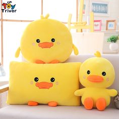 two yellow stuffed toys sitting on top of a white couch in front of a window