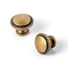 two brass knobs are shown on a white background, one has an oval design and the other has a braided edge