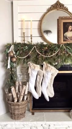 stockings hung on the mantel in front of a fireplace decorated with greenery and candles