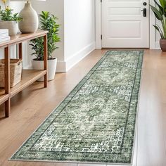 a green rug in front of a white door with potted plants on the side