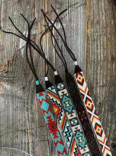 three native style necklaces are sitting on a wooden table next to some twig