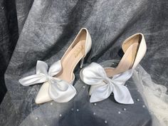 a pair of white high heels with bows on them