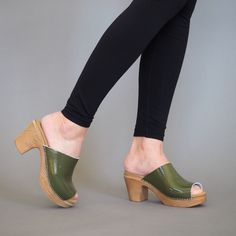 Frida is a chic open-toe mule clog that’s right on trend for this season. Here in striking patent green leather with a contrasting wood-effect sole. Not just a good looker, with its cushioned, flexible sole, the Frida clog is extremely comfortable to wear. Designed in Sweden and handmade in Italy. Flexible sole with wood-like effect Heel 7,5 cm / 2.95 In Normal fit Local European, Clogs Outfits, High Heel Clogs, Swedish Clogs, Heel Grips, Shoes Too Big, Olivia Black, Clog Heels, Wooden Shoes