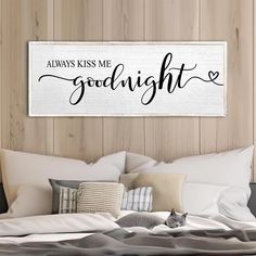 a bedroom with a bed, pillows and a wooden sign that says always kiss me goodnight