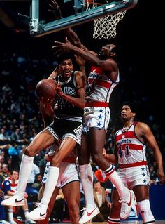 the basketball players are trying to block the ball from going into the basket during a game