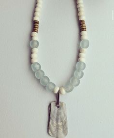 a necklace with white beads and an elephant's paw charm hangs on a wall