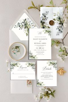 the wedding stationery is laid out on top of an envelope, with flowers and greenery