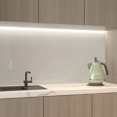 a green tea kettle sitting on top of a counter next to a faucet