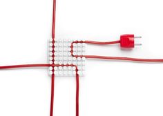 two red and white electrical wires connected to each other on a white surface with one plugged in