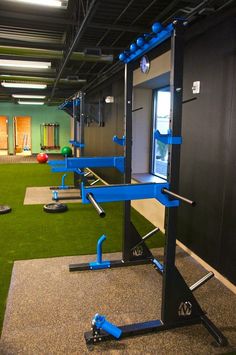 an indoor gym area with artificial turf and blue equipment on the floor in front of it