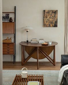 a living room with a couch, table and bookshelf next to it on the wall