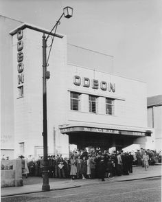 an old black and white photo of people standing in front of a theater