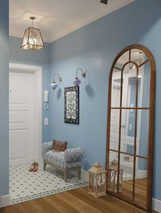 a room with blue walls and wooden floors has a mirror, bench, and lamp on the wall