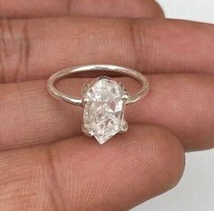 someone is holding an engagement ring with a large white diamond in it's hand