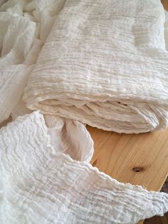 a pile of white blankets sitting on top of a wooden floor