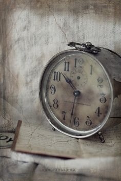 an alarm clock sitting on top of a piece of paper next to some type of book