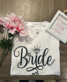 a t - shirt with the word bride on it next to flowers and a card