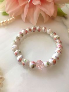 Handmade pink and white floral ceramic bead stretch bracelet. Made with 8mm ceramic beads and a light pink glass crystal. The bracelet measures approximately 7" before stretching. White Stretch Bracelet For Spring, Adjustable White Stretch Bracelet For Spring, Spring White Adjustable Stretch Bracelet, White Stretch Bracelet For Spring Gift, Cottagecore Bracelet, Pink Chinoiserie, Victorian Bracelet, Chic Bracelet, Floral Bracelet