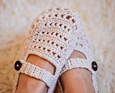 a woman's feet wearing crochet sandals on top of a carpeted floor