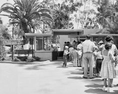 an old black and white photo of people standing in front of a building with palm trees