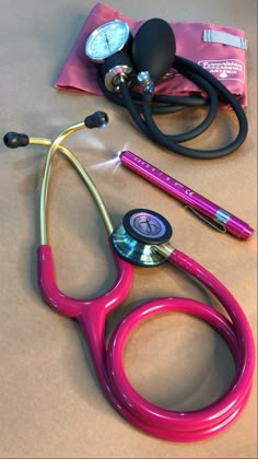 a pink stethoscope sitting on top of a table next to some medical supplies