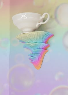 a white cup and saucer on top of a rainbow - colored background with bubbles