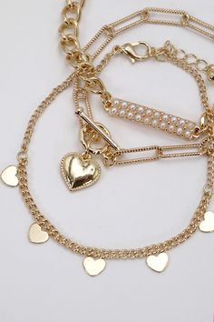 Pearl Stud Bar Heart Link Multi-Chain Bracelet Set, a captivating ensemble that beautifully combines classic pearls, modern bar details, and heart-shaped links for a unique and stylish accessory. Pearl Stud Accents: Each bracelet in this set features lustrous pearl studs. The heart-shaped links connect the various chains, infusing the bracelets with a romantic and charming vibe. The heart links serve as focal points, adding sentiment and sweetness to the overall aesthetic.DIMENSION length: 8" ex Gold Heart Beads Bracelet For Party, Elegant Pearl Heart Bracelet With Charm, Heart Shaped Pearl Bracelet, Gold Elegant Heart Beads Bracelet, Elegant Gold Heart Beads Bracelet, Multi Chain Bracelet, Sunglass Chain, Focal Points, Faux Leather Belts