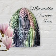 a crocheted hat with pink flowers in the foreground and text, magnifia crochet hat