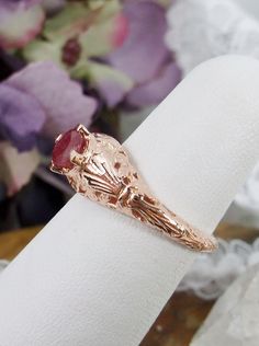 Natural Ruby Gold Ring Floral Wedding Design#154 Custom This is a Victorian reproduction wedding ring in 10K solid rose gold filigree with a natural red ruby gemstone solitaire. This full cut round gem is 4mm in diameter. The inside of the band is marked 10K for gold. Notice the beautiful floral motif in the gold filigree setting. This is a lovely rendition of an Antique filigree ring. The original ring was a floral wedding antique ring. The Edwardian influence gives it more flair and detail. El Intricate Ruby Wedding Ring, Ruby Filigree Wedding Ring, Gold Filigree Ruby Wedding Ring, Antique 14k Stamped Ruby Wedding Ring, Gold Ruby Ring With Filigree For Wedding, Heirloom Ruby Ring In Rose Gold For Anniversary, Heirloom Rose Gold Ruby Ring For Anniversary, Oval Rose Design Jewelry For Wedding, Rose Gold Engraved Ring Stamped 14k For Wedding