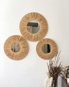 three circular mirrors hanging on the wall above a vase