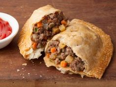 a meat and vegetable pie next to a bowl of ketchup