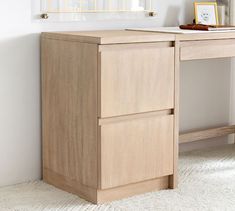 a wooden desk with two drawers and a mirror on the wall in a white room