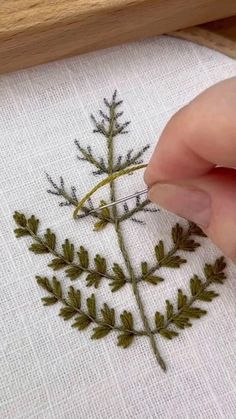 someone is stitching leaves on a piece of cloth