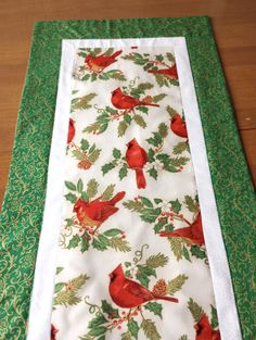 a table runner with red birds and holly on it