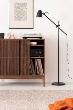 a record player is sitting on top of a cabinet next to a floor lamp and an orange rug