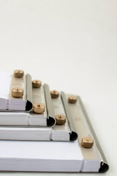 three binders are stacked on top of each other, with gold and black buttons