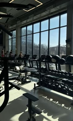 there are many treadmills in the gym with people sitting at them and looking out the windows